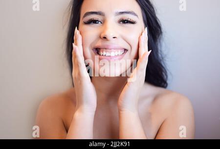 All things beauty. Portrait of a beautiful young woman applying moisturiser to her skin at home. Stock Photo