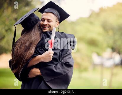 We should have our own little celebration later. a young man hugging his friend on graduation day. Stock Photo