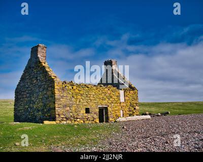 An abandoned, derelict croft or farm house with no roof on a pebble beach at Stenness, Northmavine in  Shetland, Scotland, UK. Stock Photo