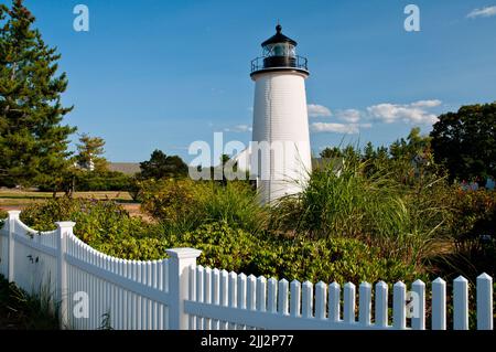 White picket fence in front of Newburyport Harbor lighthouse, also known as Plum Island light in northern Massachusetts on a summer day. Stock Photo