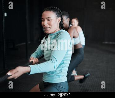 Women doing it for themselves. a group of young women pulling a rope in a game of tug of war at the gym. Stock Photo