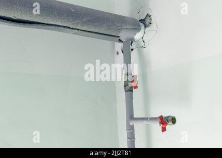 metal water pipes on the wall in a room with valves and fittings Stock Photo