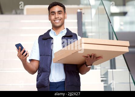 Bringing joy to the masses. a young delivery man delivering a pizza ordered using a smartphone. Stock Photo