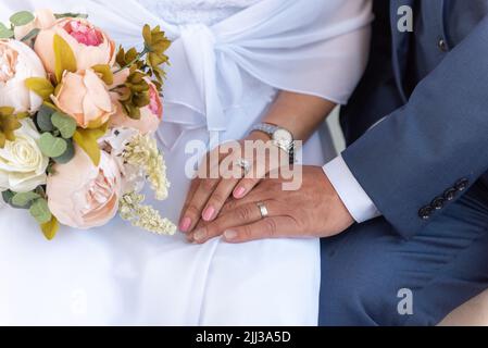 Bride's hand on top of the grooms to show the wedding rings exchanged duriing the marriage ceremony. Stock Photo
