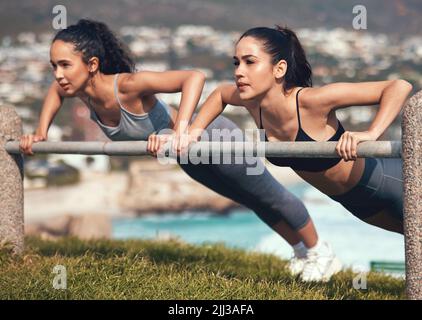 No rest for the wicked. two young friends doing push ups together. Stock Photo