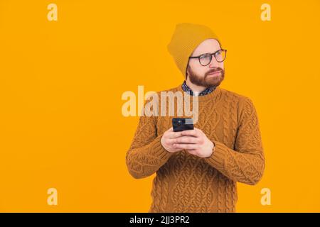 Young stylish online trader investor thinking about new investments and trades - passive income concept - orange background. High quality photo Stock Photo