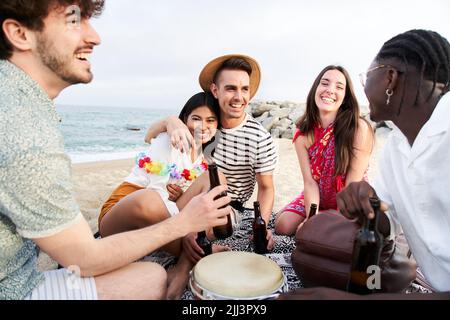 People Celebration Beach Party Summer Holiday Concept. Five beautiful friends cheers and drink beers near the sea, enjoying vacation time laughing and Stock Photo