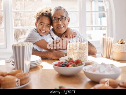 You should live everyday like its your birthday. a Grand daughter hugging her grandpa during a birthday party at home. Stock Photo