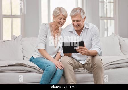 Better together. a elderly couple using a tablet at home. Stock Photo