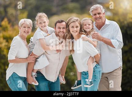 Portrait of a smiling multi generation caucasian family standing close together in the garden at home. Happy adorable girls bonding with their mother Stock Photo