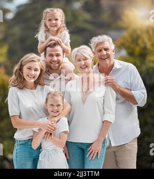 Mature and young family members outside in the garden. Happy smiling parents relaxing outside with their children. Portrait of content grandparents Stock Photo