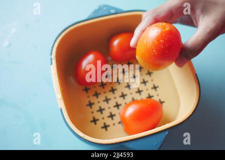 cleaning fresh tomato with a water in a plastic bowl  Stock Photo