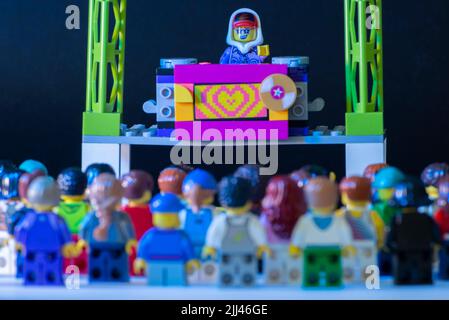 Lego DJ minifigure performing a show on stage with thousands of spectators watching and having fun. Rave party with lots of electronics and dancing. m Stock Photo