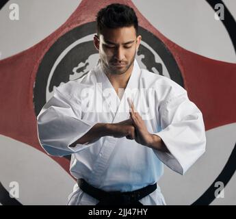 Showing respect to his opponent. a handsome young martial artist practicing karate in his dojo. Stock Photo