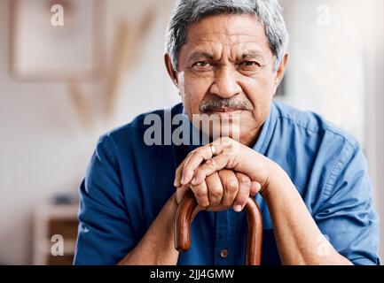 I dont have time for your questions. a senior man leaning in his walking stick at home. Stock Photo