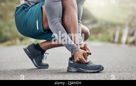 Im wearing my most comfortable running shoes. an athletic man tying his laces while our for a run. Stock Photo