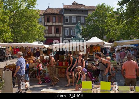 Limoux Aude France 07.22.22 Market square. Stall selling colourful bags and sun hats. Young family, three children . Mature man and woman. Summer Stock Photo