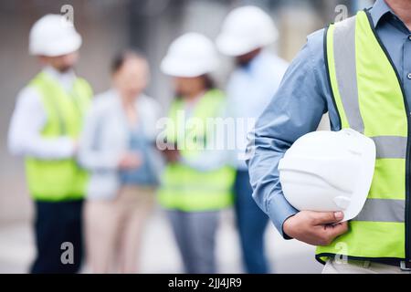 We put safety first. an unrecognizable architect holding a helmet at a building site. Stock Photo