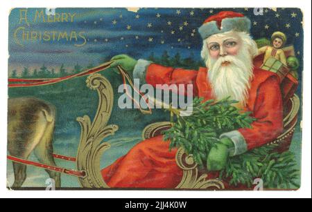 Original Edwardian era embossed Victorian Christmas card, postcard of Santa with sack of toys, holding a Christmas tree, riding in a star-lit night in a sleigh pulled by reindeer, circa 1910 Stock Photo