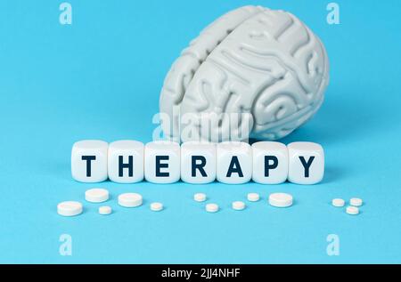Medicine and health. Cubes lie on the table among the pills and imitation of the brain. The text on the dice - THERAPY Stock Photo