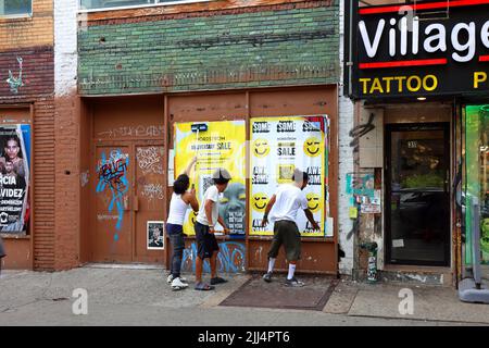 People wheatpasting advertising posters on a wall, or wild posting advertisments, as part of an street-level, guerilla, urban marketing campaign. Stock Photo
