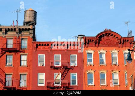 New York City tenement buildings in Manhattan's Greenwich Village neighborhood near sunset with wooden water tank and rooftop tv attennas. Stock Photo