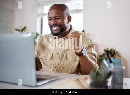This day couldnt get any better. a mature businessman using a laptop and looking excited in a modern office. Stock Photo
