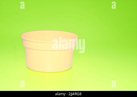 Delicate cream plastic jar capacity of isolated on green yellow Stock Photo