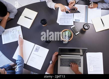 Lay it all on the table. an office table with staff using a digital tablet and laptop. Stock Photo