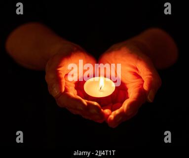 We have always held to the hope. a unrecognizable person holding a candle in the dark. Stock Photo