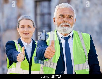 Always be the hardest worker in the room. two engineers giving thumbs up while standing outside on a construction site. Stock Photo
