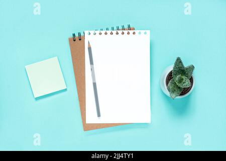 Notebook with pencil. School notebook on light blue background, spiral notepad on table. Top view of open notebook with blank pages, office notepad Stock Photo