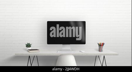Computer monitor on work desk with brick wall in background. Blank screen for mockup, web design presentation. Work desk with books and pens Stock Photo