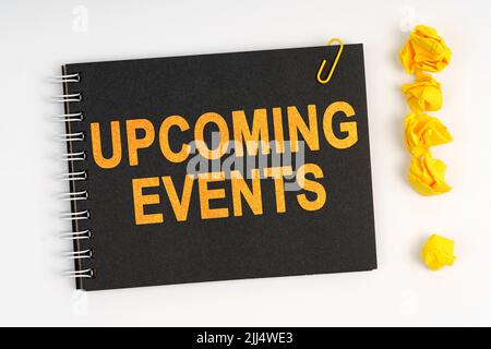 Business concept. On a white background lies a marker, an exclamation mark made of paper and a notebook with the inscription - UPCOMING EVENTS Stock Photo