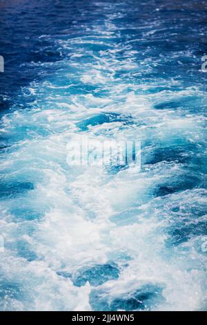 Wave trace tails of speed boat on a blue water surface in the sea Stock Photo