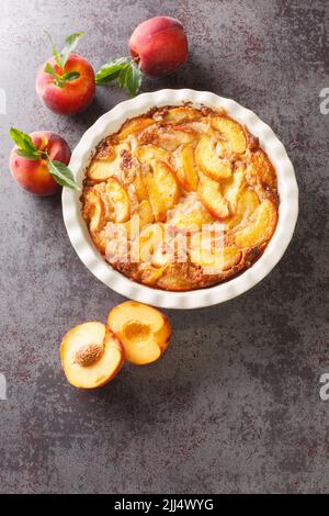 Homemade peach cobbler crumble in baking dish over concrete gray background. Vertical top view from above Stock Photo