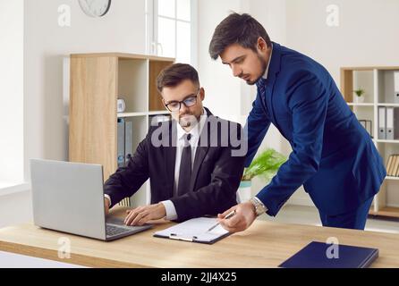 Two business people meet in the office, talk, work with documents and use computer Stock Photo