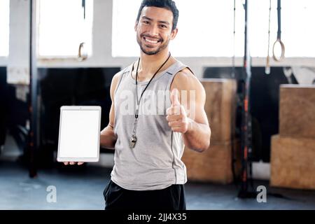 Ive worked out a schedule for you. a young man showing thumbs up while using a digital tablet in the gym. Stock Photo