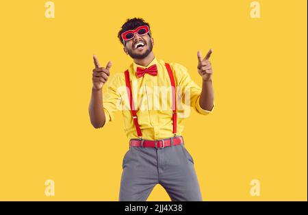 Funny stylish bearded indian guy having fun and dancing isolated on orange background. Stock Photo