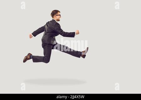 Funny businessman or office worker hurrying to work meeting isolated on grey background Stock Photo