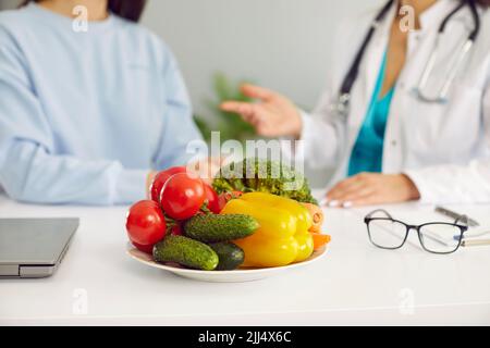 Fresh vegetables in plate cucumbers, tomatoes and bell peppers on table of nutritionist doctor Stock Photo