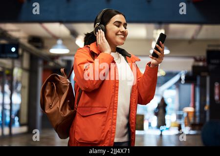I need some music motivation for this day. a young female student using a phone at college. Stock Photo