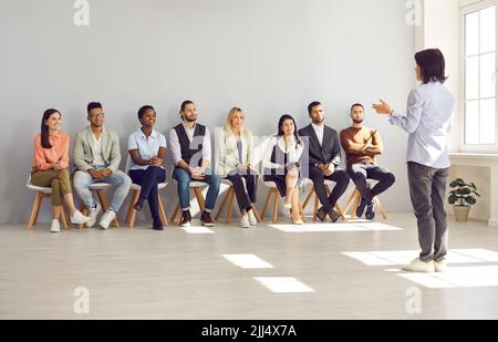 Business speaker or psychologist giving a speech for young diverse men and women Stock Photo
