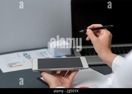 Businesswoman Holding Mobile Phone And Pen Pointing On Important Message. Woman In Suit Having Pencil In Hand And Presenting Critial Information Stock Photo