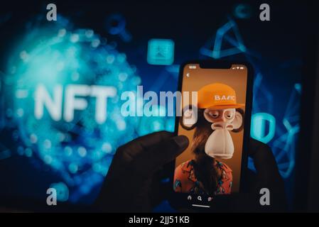 Hand holding a mobile phone showing an NFT Stock Photo