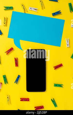 Pegs Placed Around Phone And Speech Bubble With Important Informations. Colorful Pins Arranged All Over Dialogue Balloon And Cellphone Screen With Stock Photo