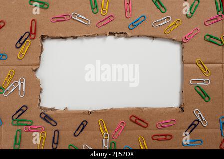 Important Informations Written Under Ripped Cardboard With Colored Paperclips Around. Crutial Announcements Underneath Torn Paperboard With Colorful Stock Photo