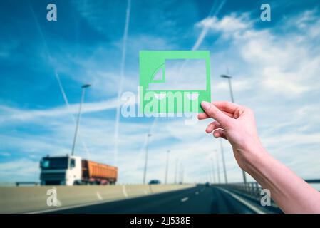 Hand holds green logistics symbol against highway Stock Photo