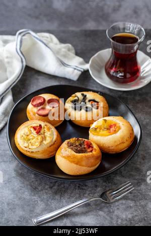 Small assortment of pizzas. Snack pizza on dark background. Bakery products. Vertical view. Close-up. Stock Photo