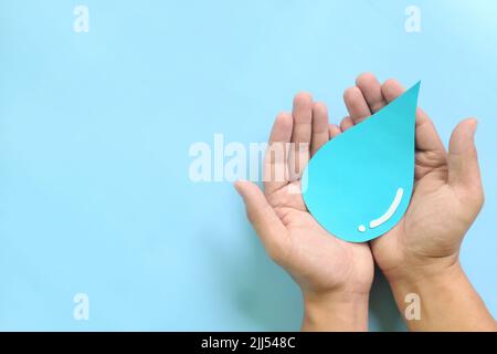 Water conservation and access to safe drinking water concept. Top view of human hands holding blue water drop with copy space. Stock Photo